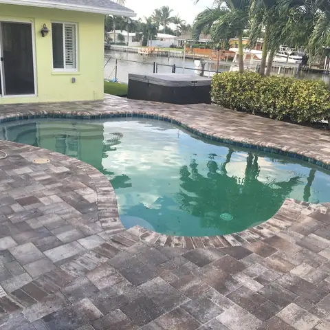 Sealed pavers around a kidney-shaped pool on the water