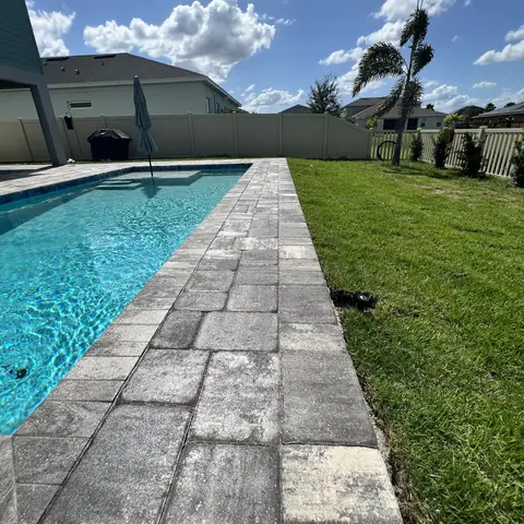 Long sealed paver walkway along a pool