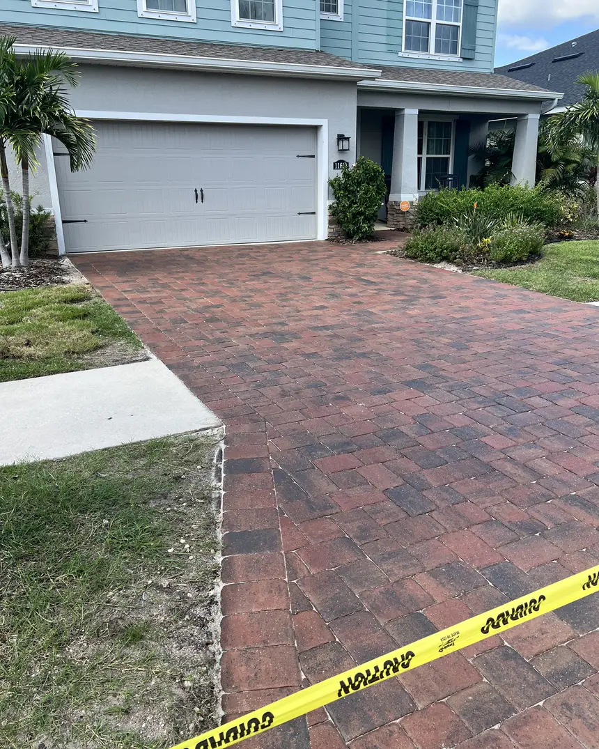 Freshly sealed red paver driveway taped off while the sealer cures